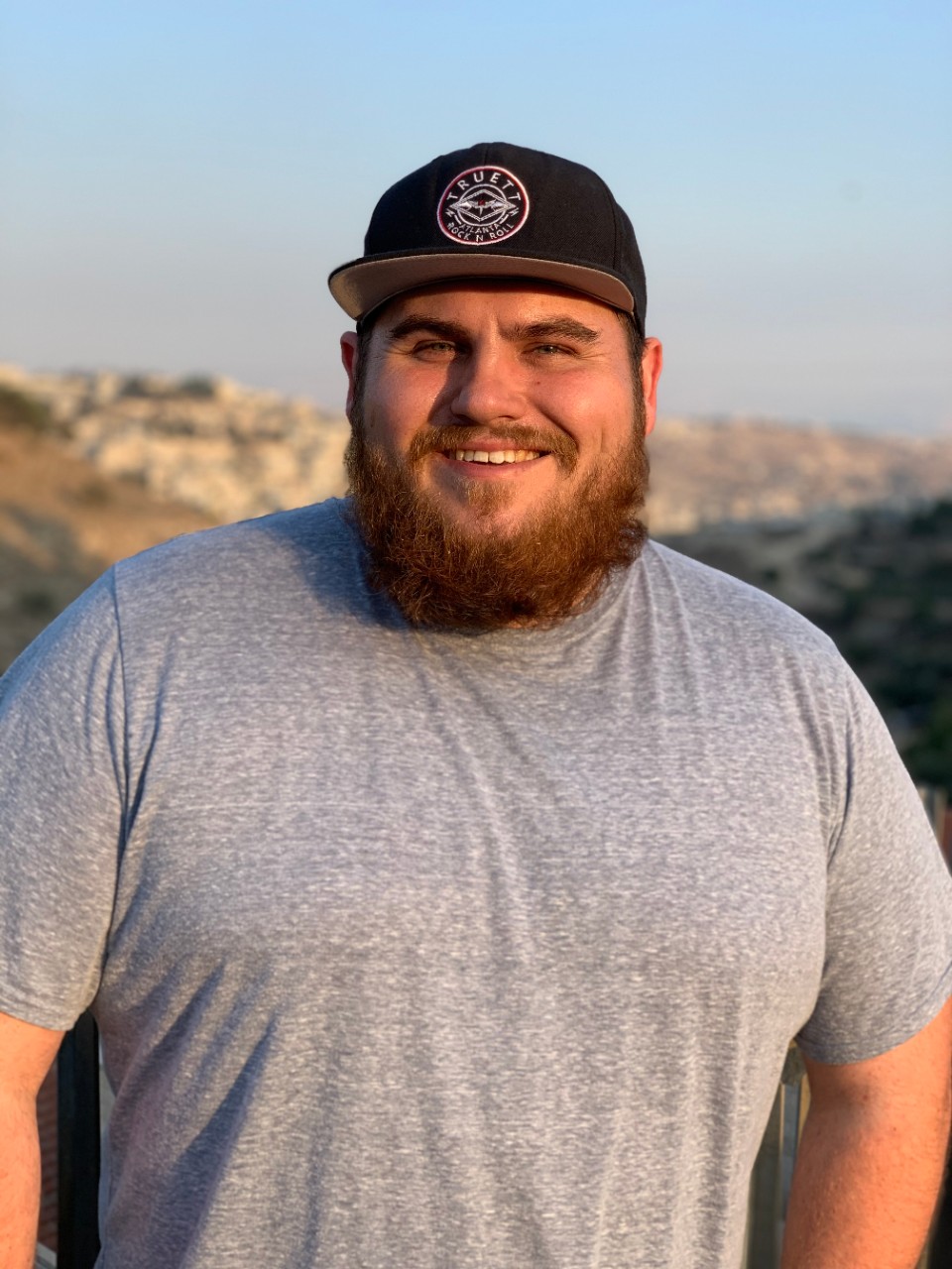 Ryan Thomas smiling with mountains behind him. 