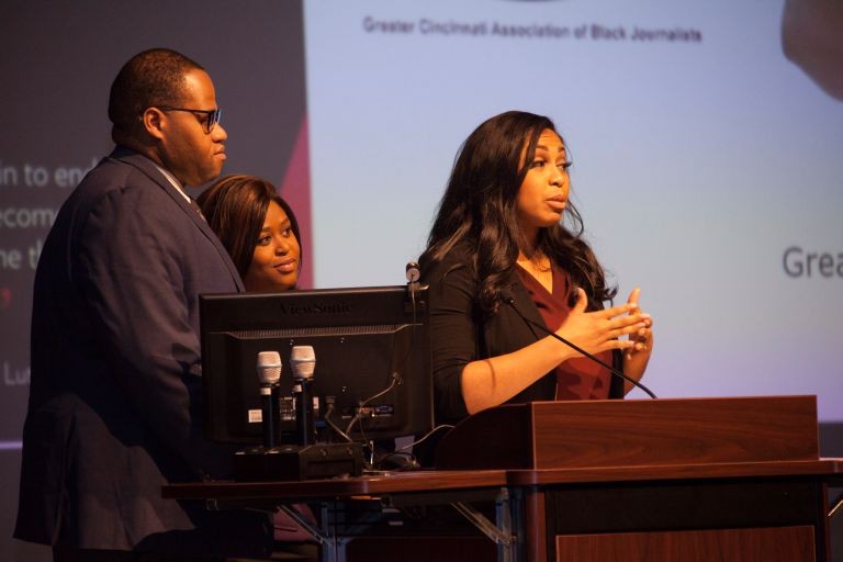picture of Alexis Rogers at speaker podium with two of her colleagues