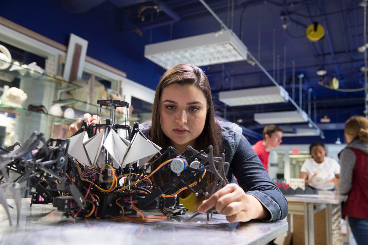 Woman studying a mechanical device in an open lab space