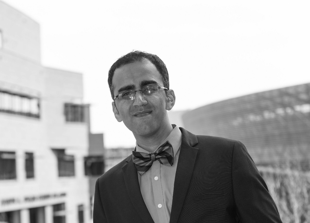 Student in suit and bow tie poses outside a campus building