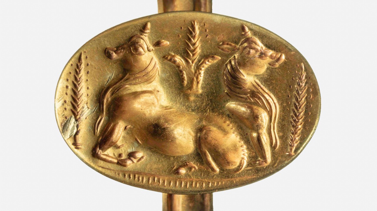 A gold ring depicts bulls and barley.