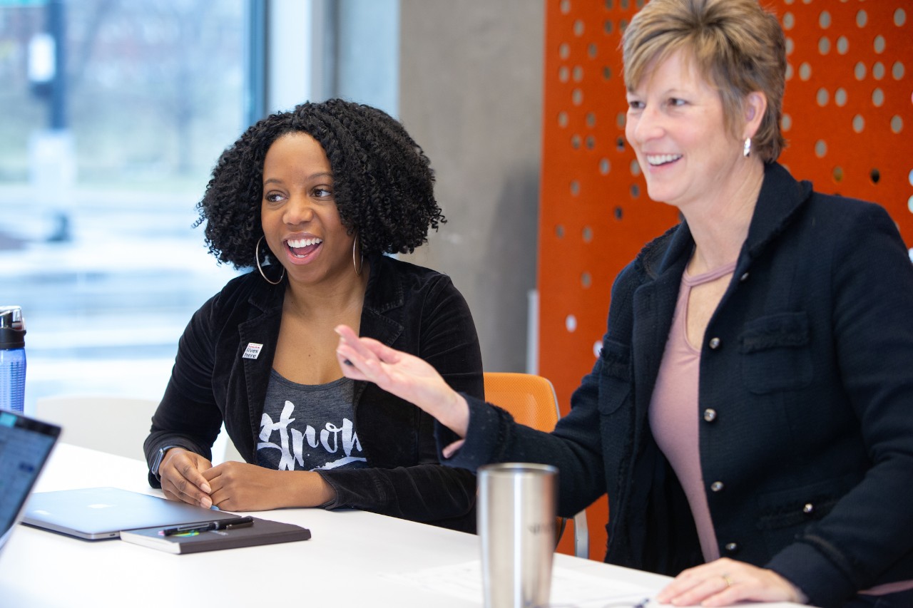 Two women sitting at a table smiling and talking