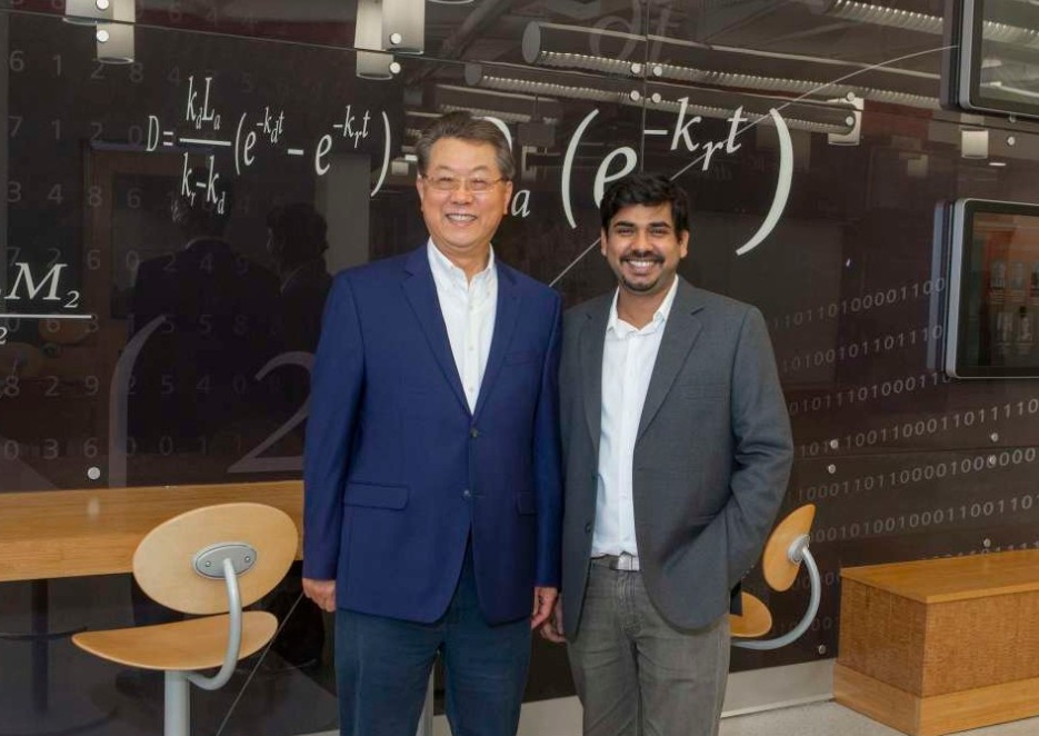 Chong Ahn and Sthitodhi Ghosh stand in front of a decorative wall featuring an equation. 
