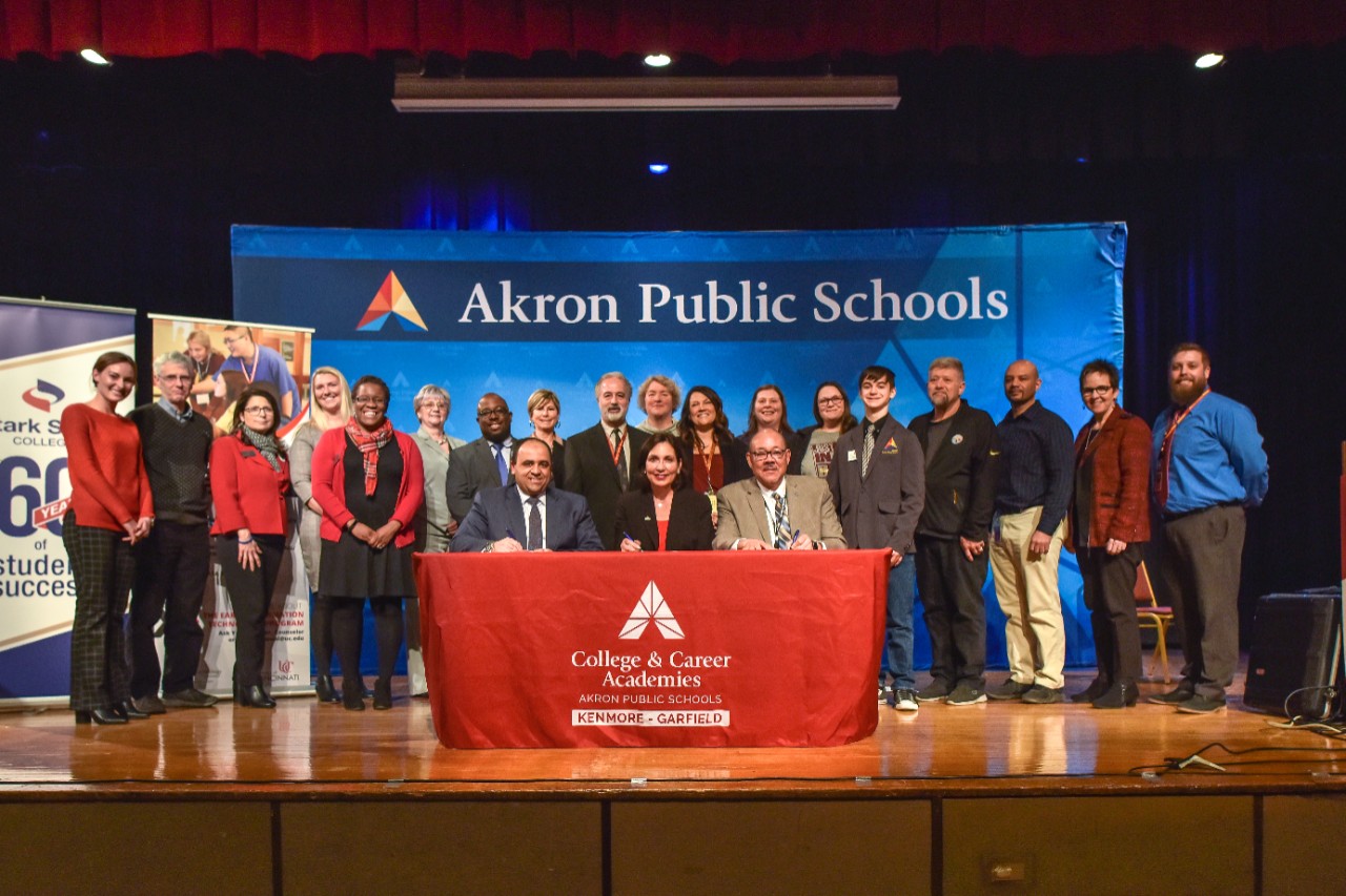 Educators stand on stage in front of a banner for Akron Public Schools.