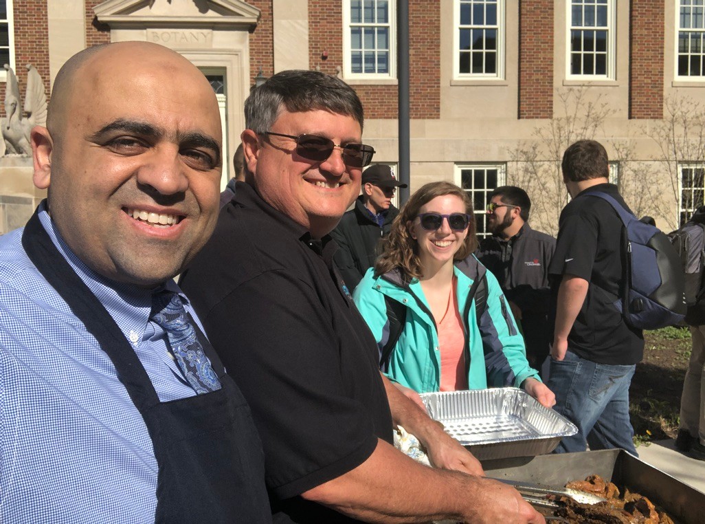 Hazem Said serves food in a chef's apron during a campus cookout.