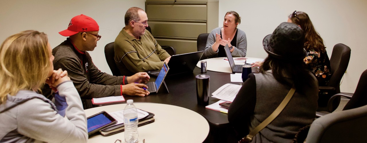 Six members of UC's Staff Senate sit around table at a meeting.