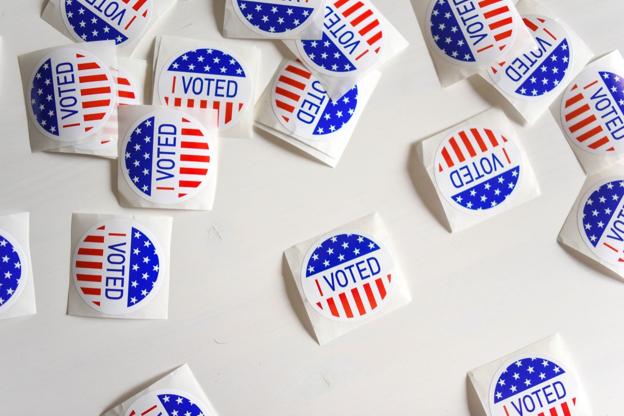 red, white and blue voting stickers torn from the roll and individually lying on a table 