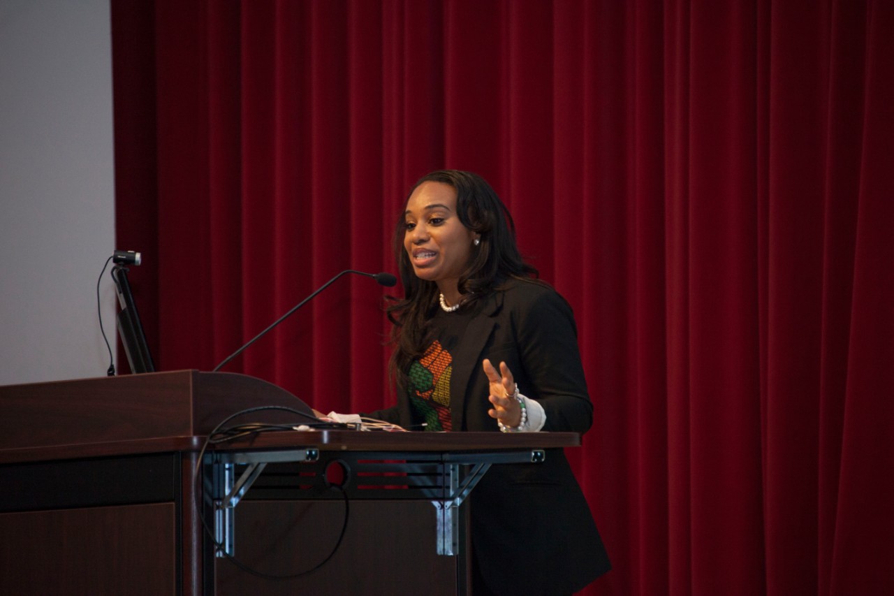 A woman speaks at a podium in an auditorium