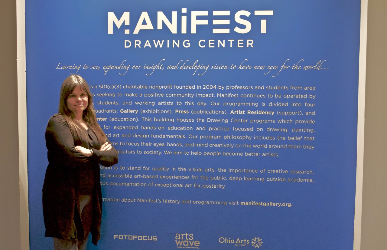 UC's Brigid O'Kane stands next to the entry wall at Manifest Drawing Center.