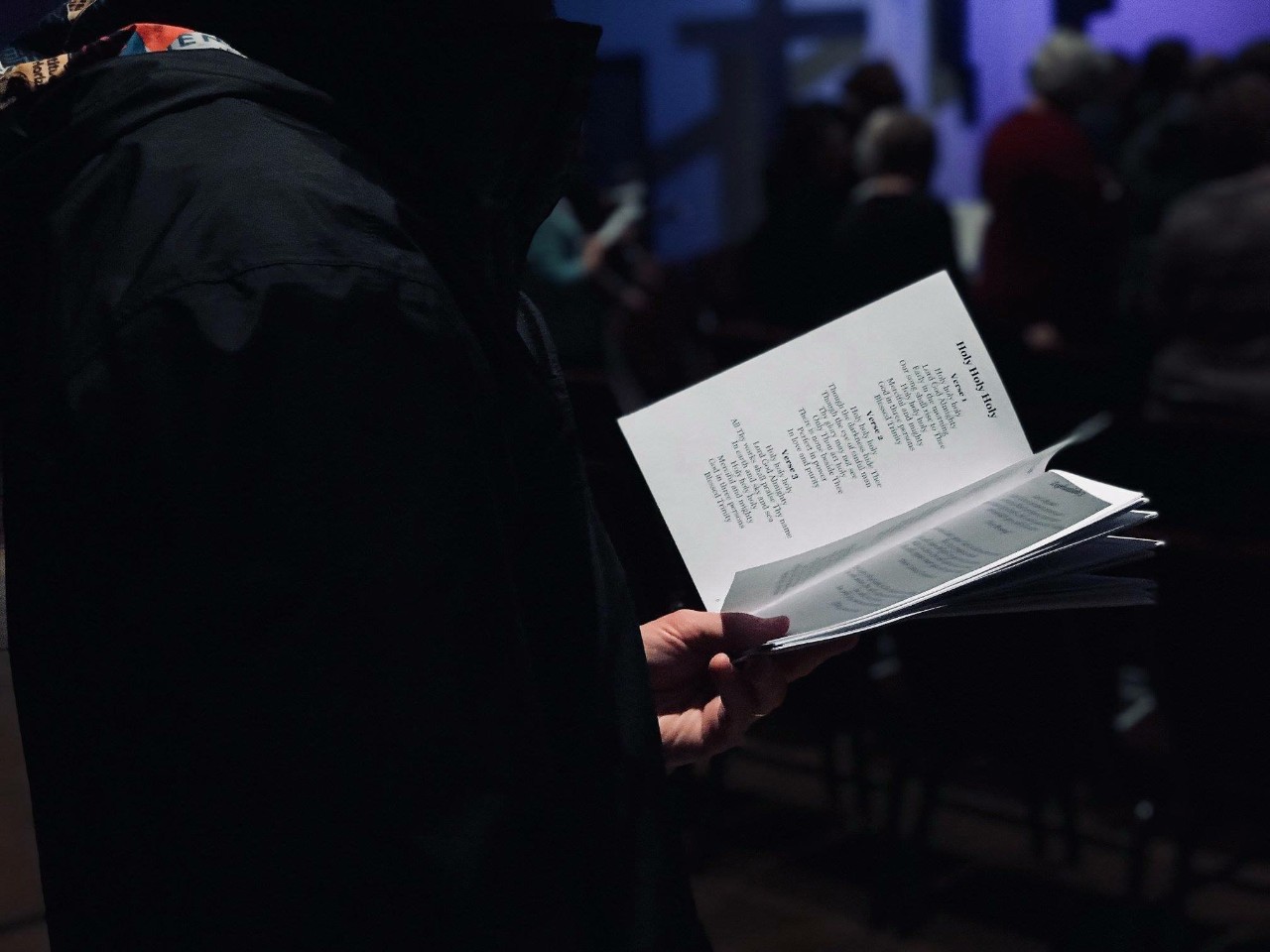 View of someone sitting in church holding music sheet 