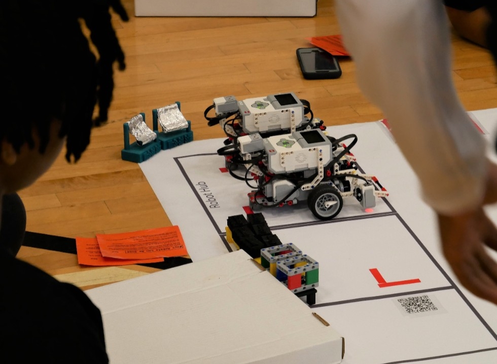 a close up on two tissue box-sized lego robots on wheels