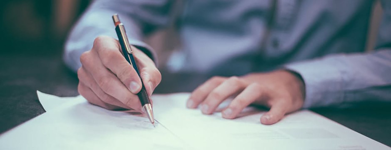 Business man with nice pen writing on paper on a table.