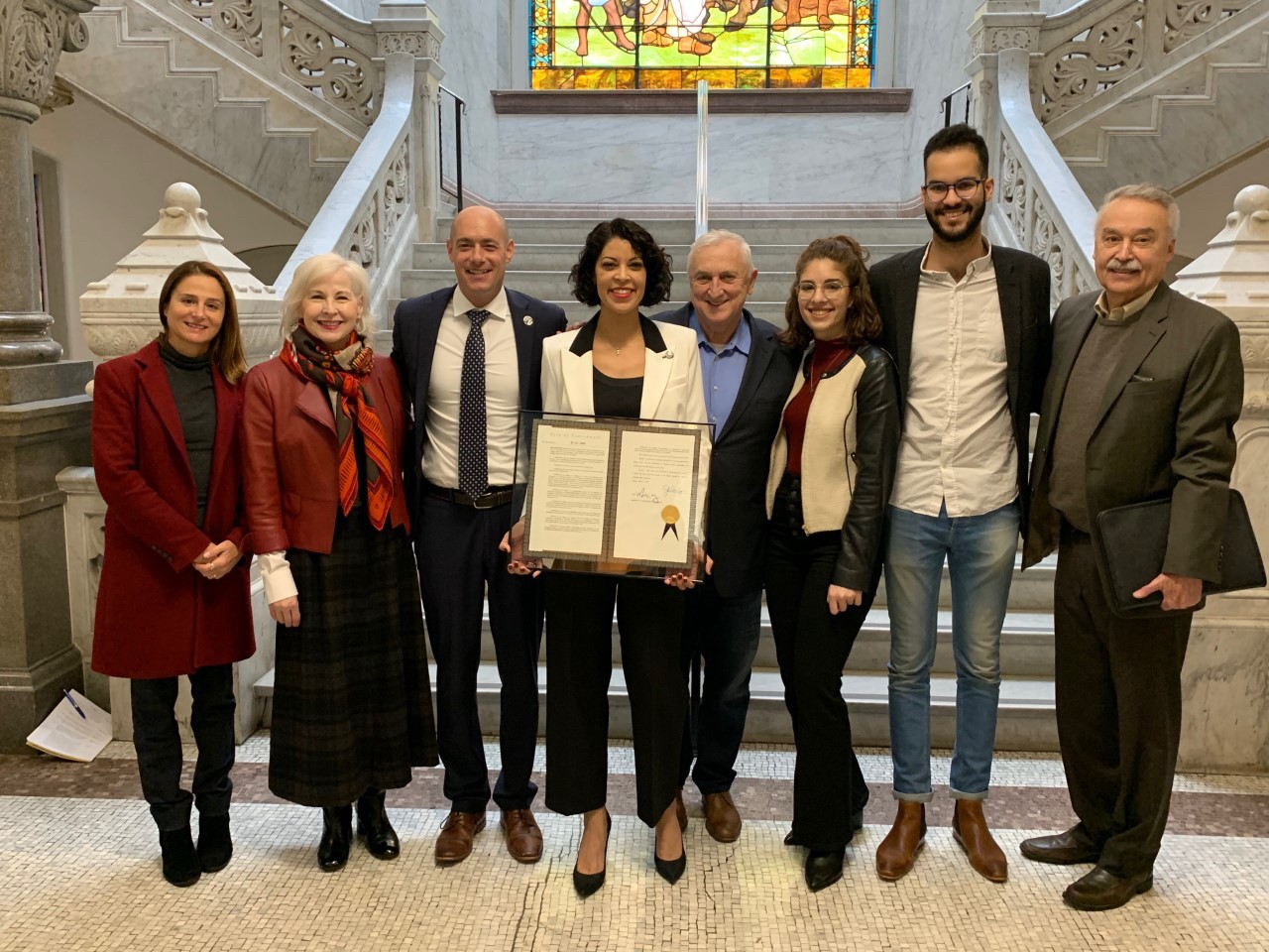 UC's Flavia Bastos stands with city dignitaries holding her Cincinnati resolution for her research in art education..