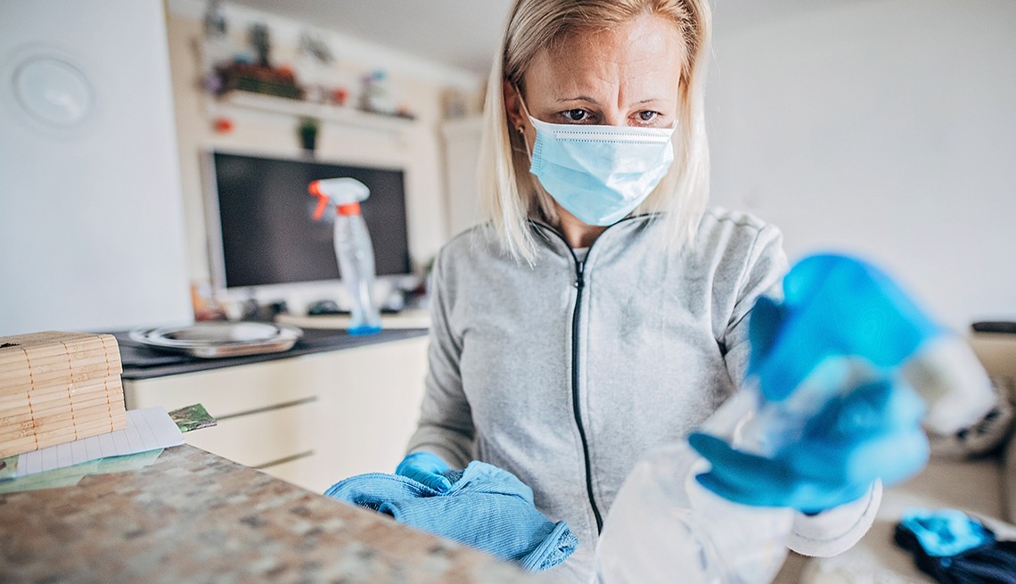 A woman wearing a surgical mask and gloves cleaning 