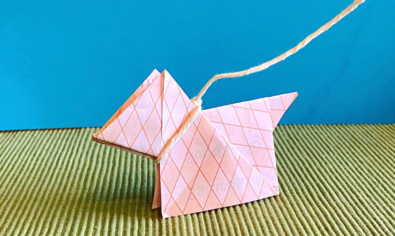 Pink paper origami dog with string leash