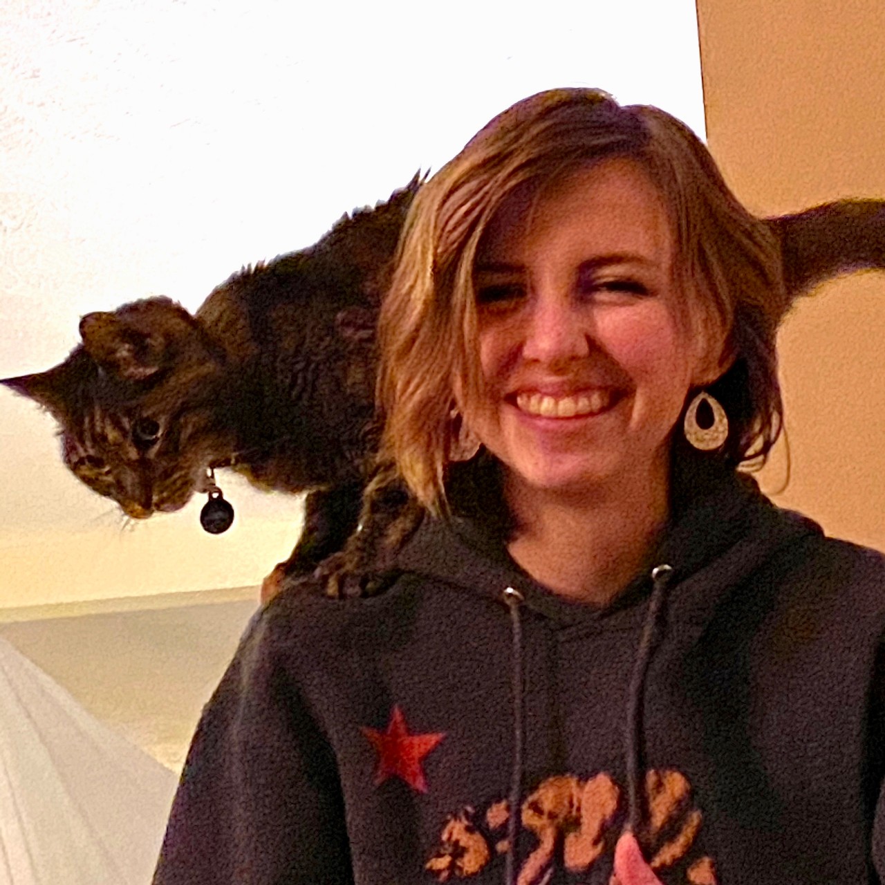 Woman with striped cat on her shoulders.