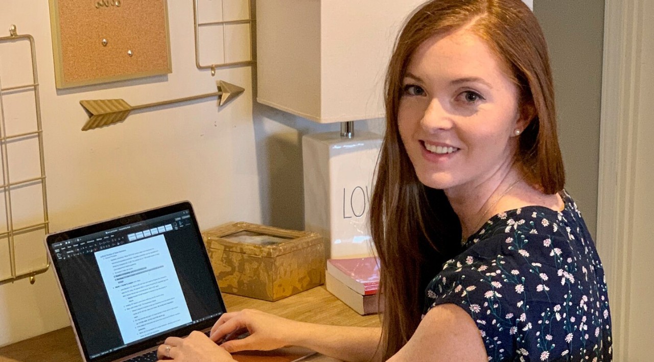 a young woman sits typing at a laptop