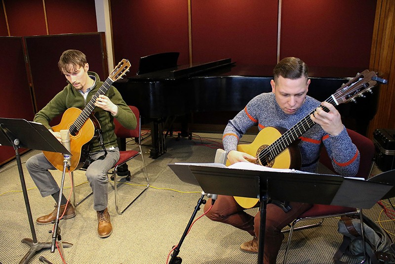 Two students play guitars in a recording studio