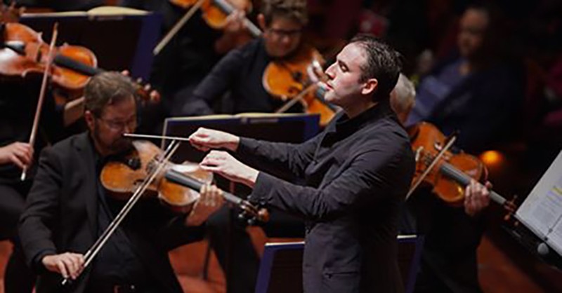 A man conducting an orchestra on stage