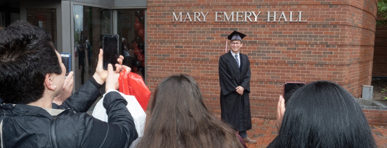 Families take pictures of their graduates in front of the CCM building