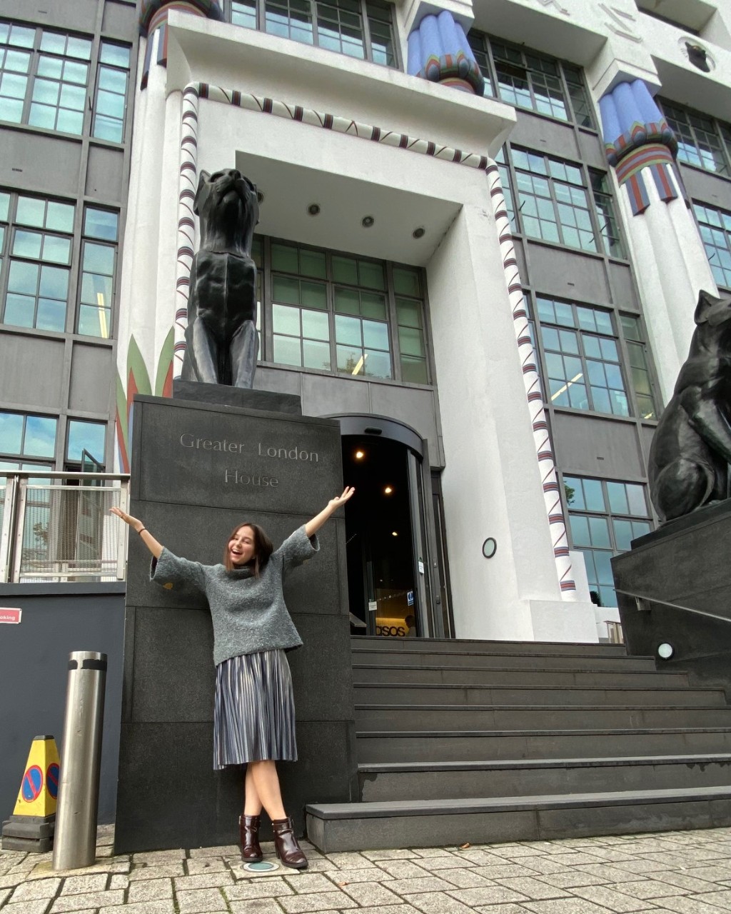 student standing with arms outstretched in front of an imposing office building