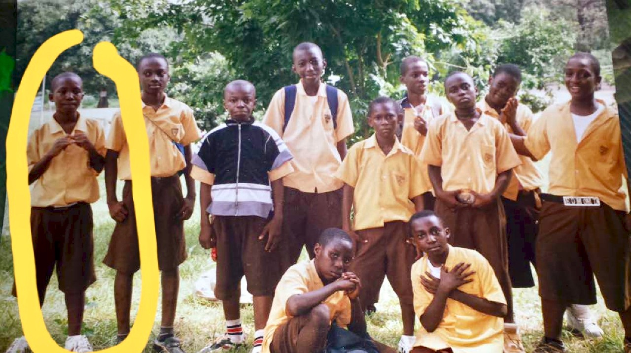 UC's Nana Agyeman and a group of young African boys stand together.