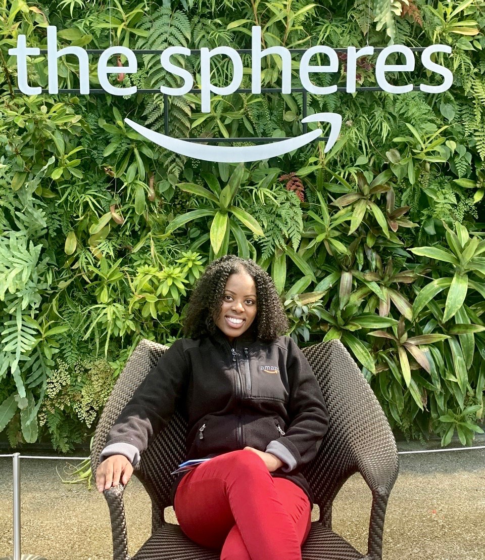 UC's Angela Brown sits in front of the tropical greens in the Amazon Corp. courtyard.