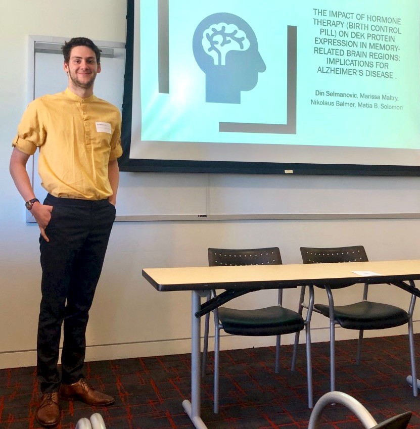 UC's Din Selmanovic stands near a poster he presented on Alzheimer's disease research.