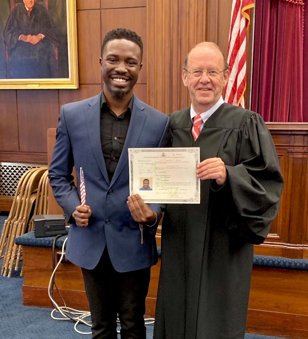 UC's Nana Agyeman stands with a Hamilton County judge holding his U.S. citizenship certificate.