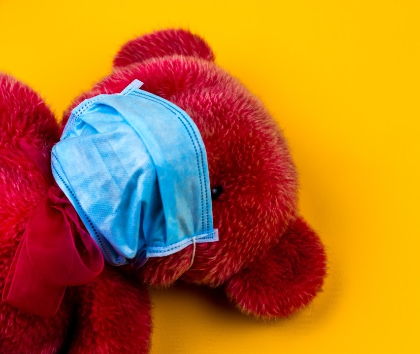 A teddy bear wears a facemask.