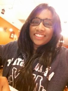 a woman wearing glasses and a sweatshirt smiling at the camera