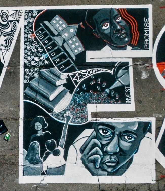 A large letter E painted on a street with figures that represent the power of education.