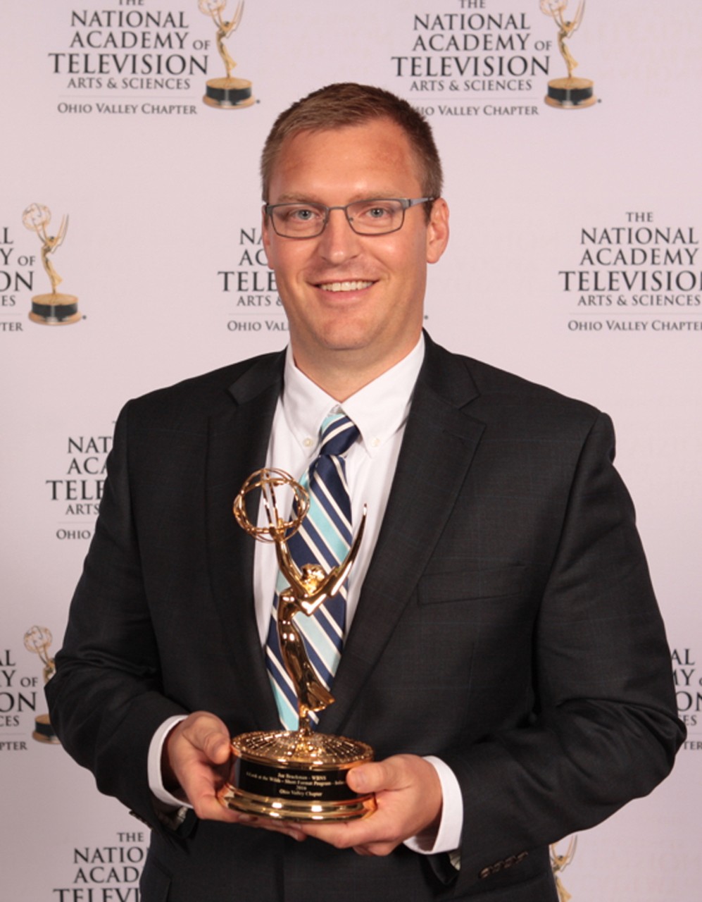 A photo of Assistant Professor of Multi-Camera Production Joe Brackman holding a Emmy Award.