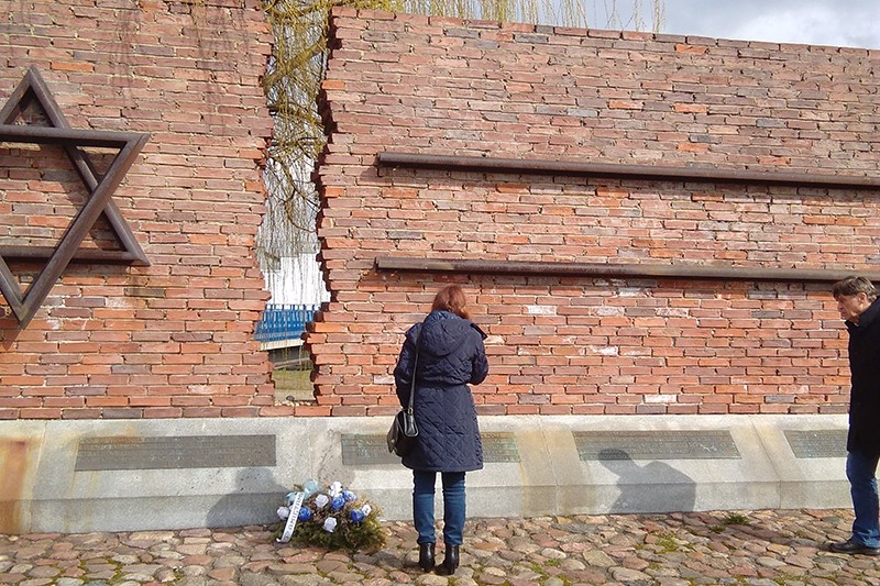 A woman stands in front of a Jewish monument at what's left of a train station