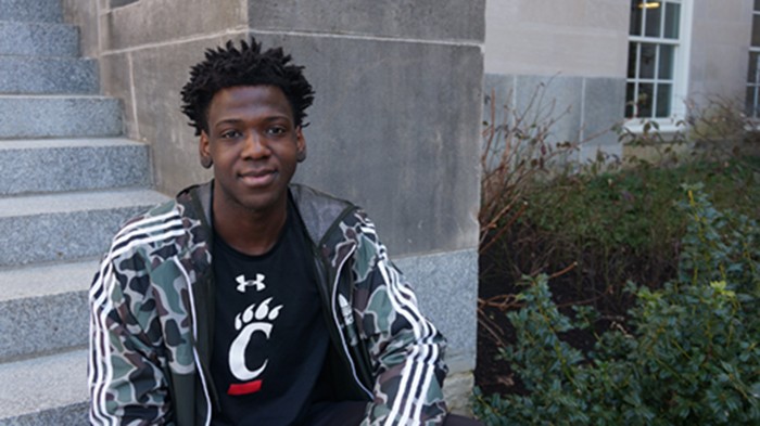 Kikonda sits on the steps outside a UC college building