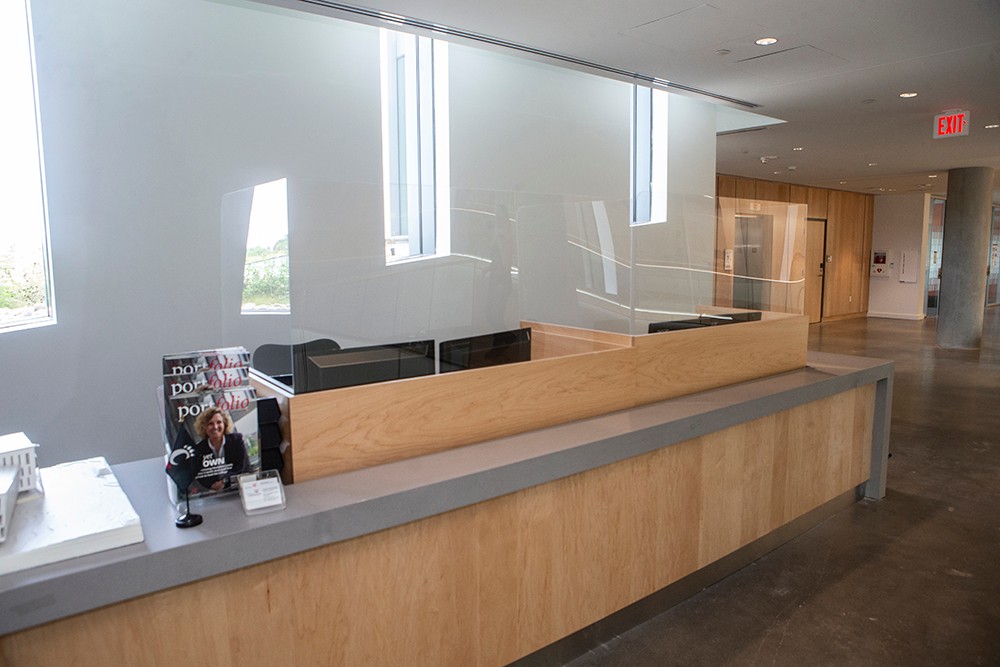 Detail shot of desk with Wellness screen and partition at Lindner College of Business (LCOB). University of Cincinnati efforts around health / safety on campus, e.g., Wellness screen partition, decals, furniture arrangements, hand sanitizer stations, tape over seating areas, exercise equipment spaced out. UC/Joseph Fuqua II