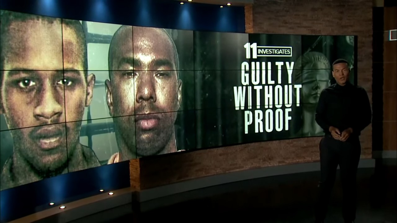 news anchor standing in front of large screen featuring two men's faces