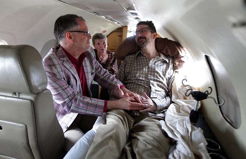 Jim Obergefell (CECH, ’90), left, and John Arthur (Bus, ’88), who suffered from ALS, were married by officiant Paulette Roberts, Arthur’s aunt, on a plane on the tarmac at Baltimore-Washington International Marshall Airport on July 11, 2013. (Photo credit: Glenn Hartong/AP)