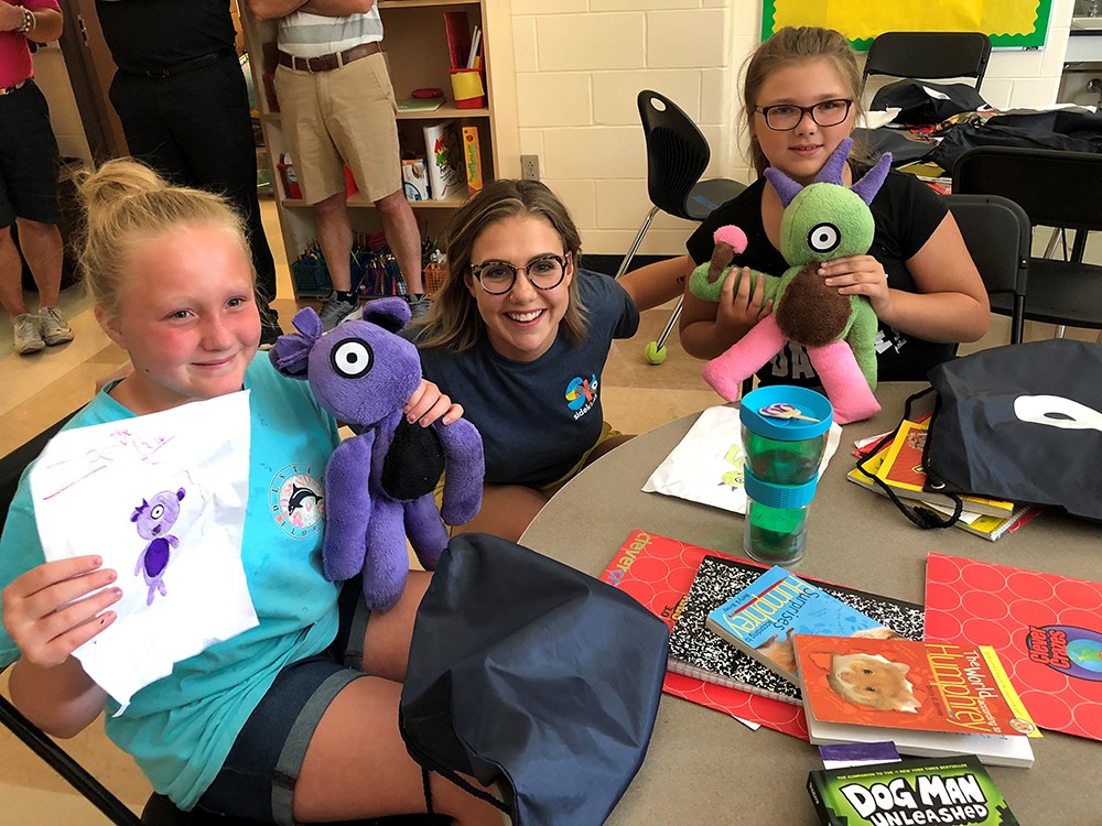 Macy Meyer (DAAP, ’18) poses with two children who she made a Sidekick stuffed animal for