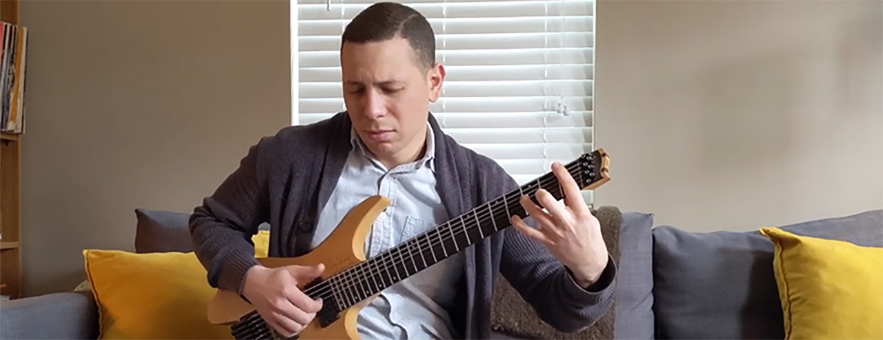 Luke Jackson playing the guitar on a couch
