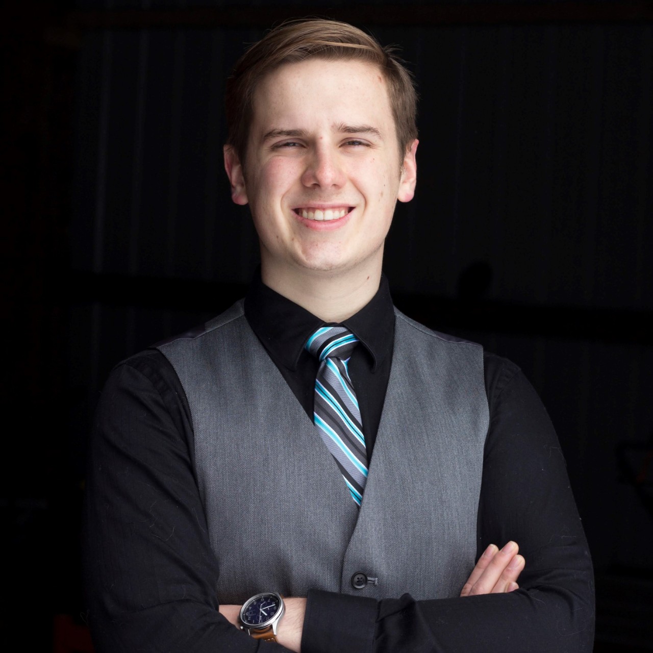 young man in a black dress shirt and silver vest