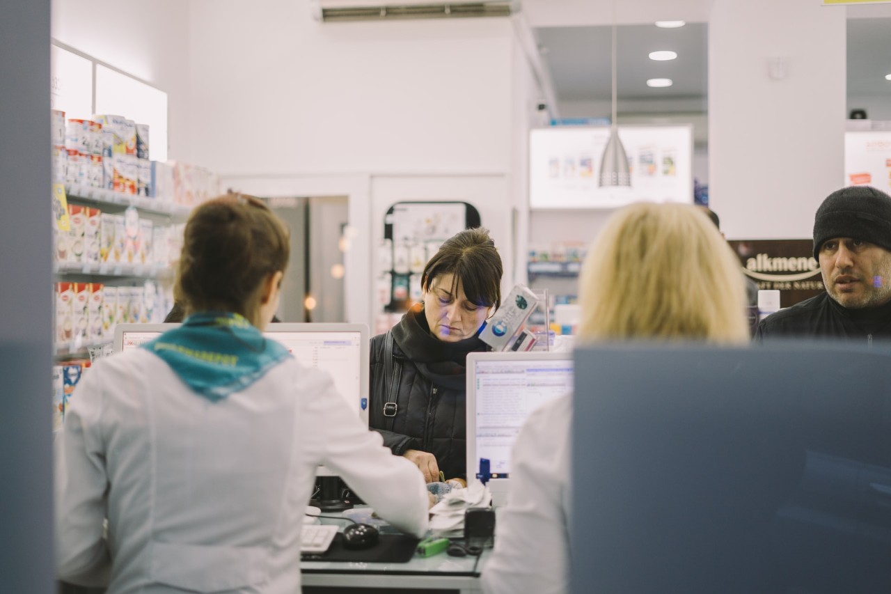 customers in a pharmacy getting prescriptions filled.