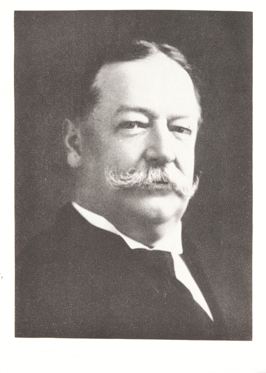 Black and white historical photo of a white man with handlebar mustache