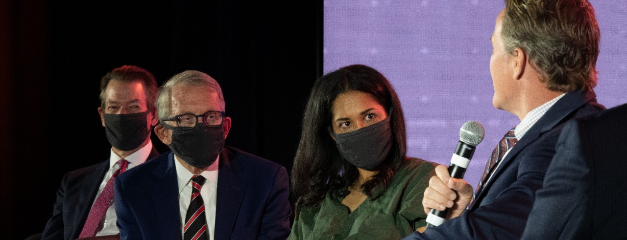 Four people on a stage during a presentation.