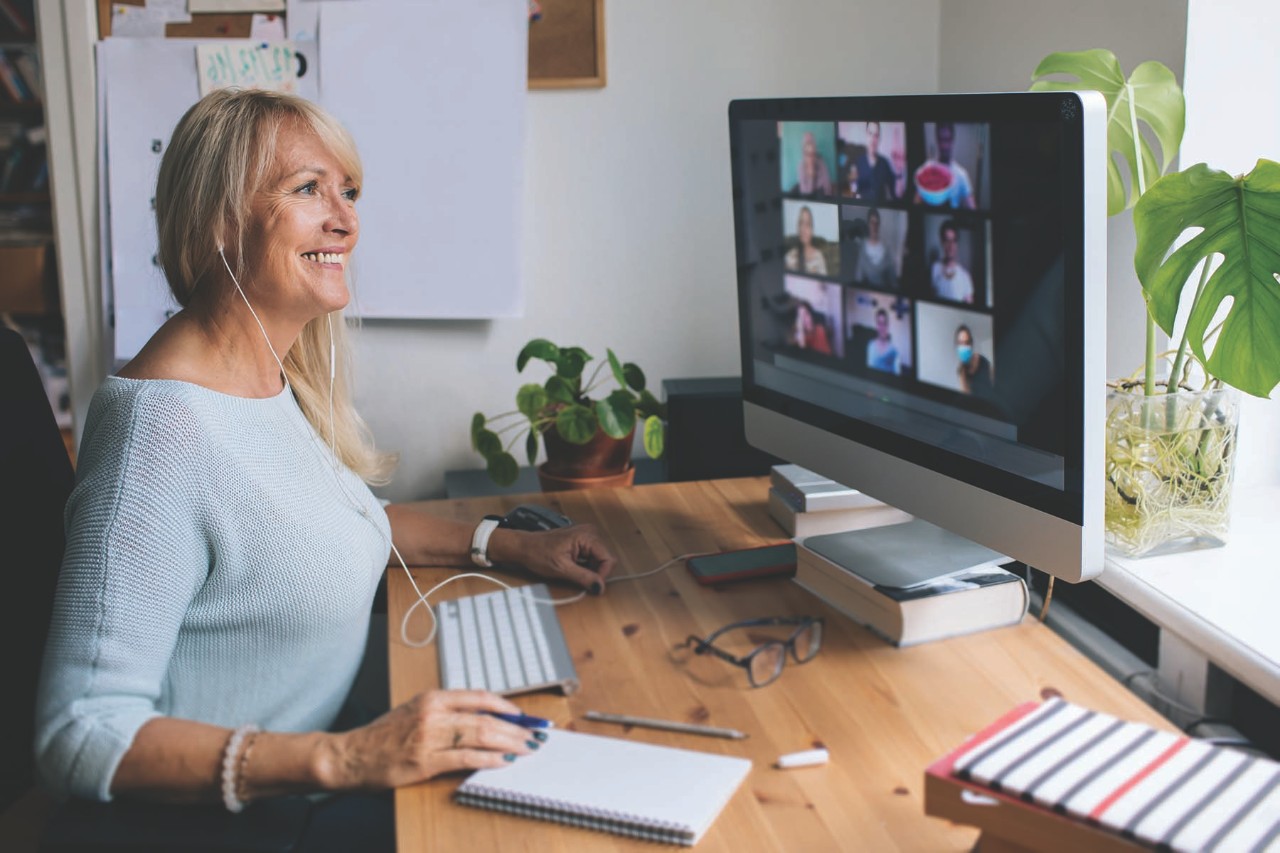 Smiling mature woman having video call via computer in the home office. Online team meeting video conference calling from home. Attractive Businesswoman Telework. Business video conferencing.