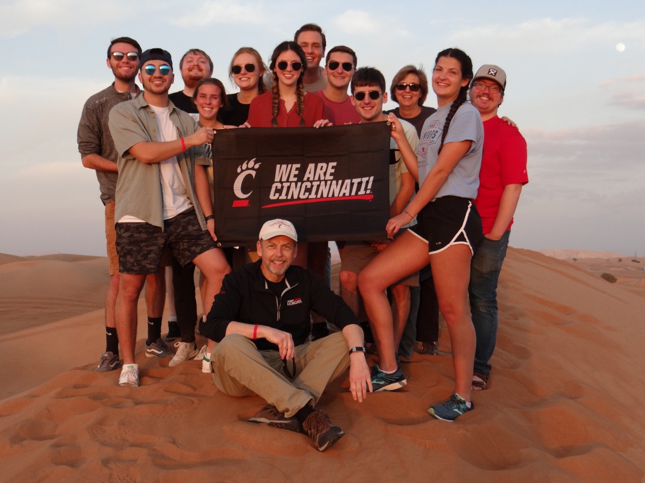 A group stands atop a sand dune.