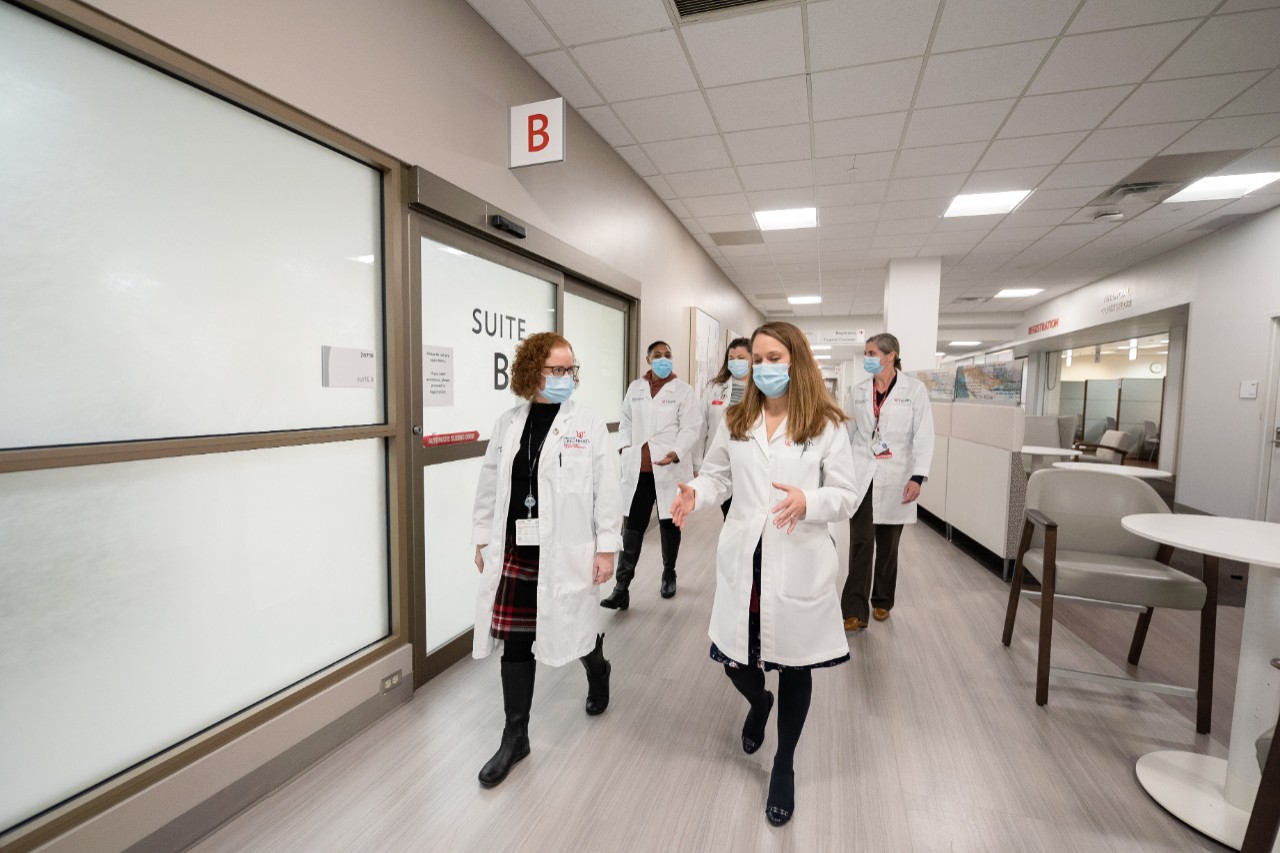 Dr. Wise-Draper and four colleagues walk and talk in the halls of a hospital