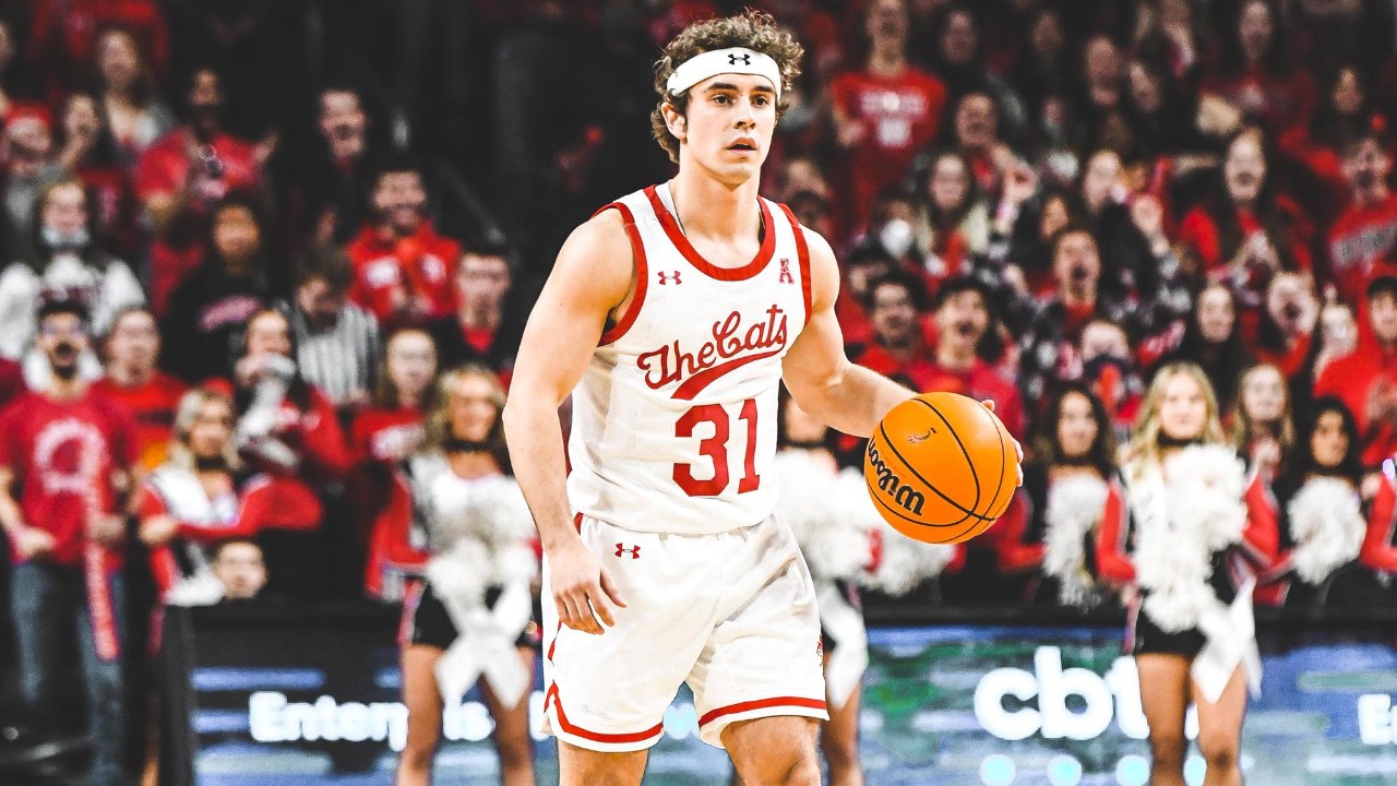 A basketball player in a white jersey with red trim dribbles the ball.