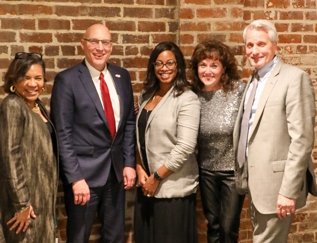 Three women and two men pose in dressy clothes