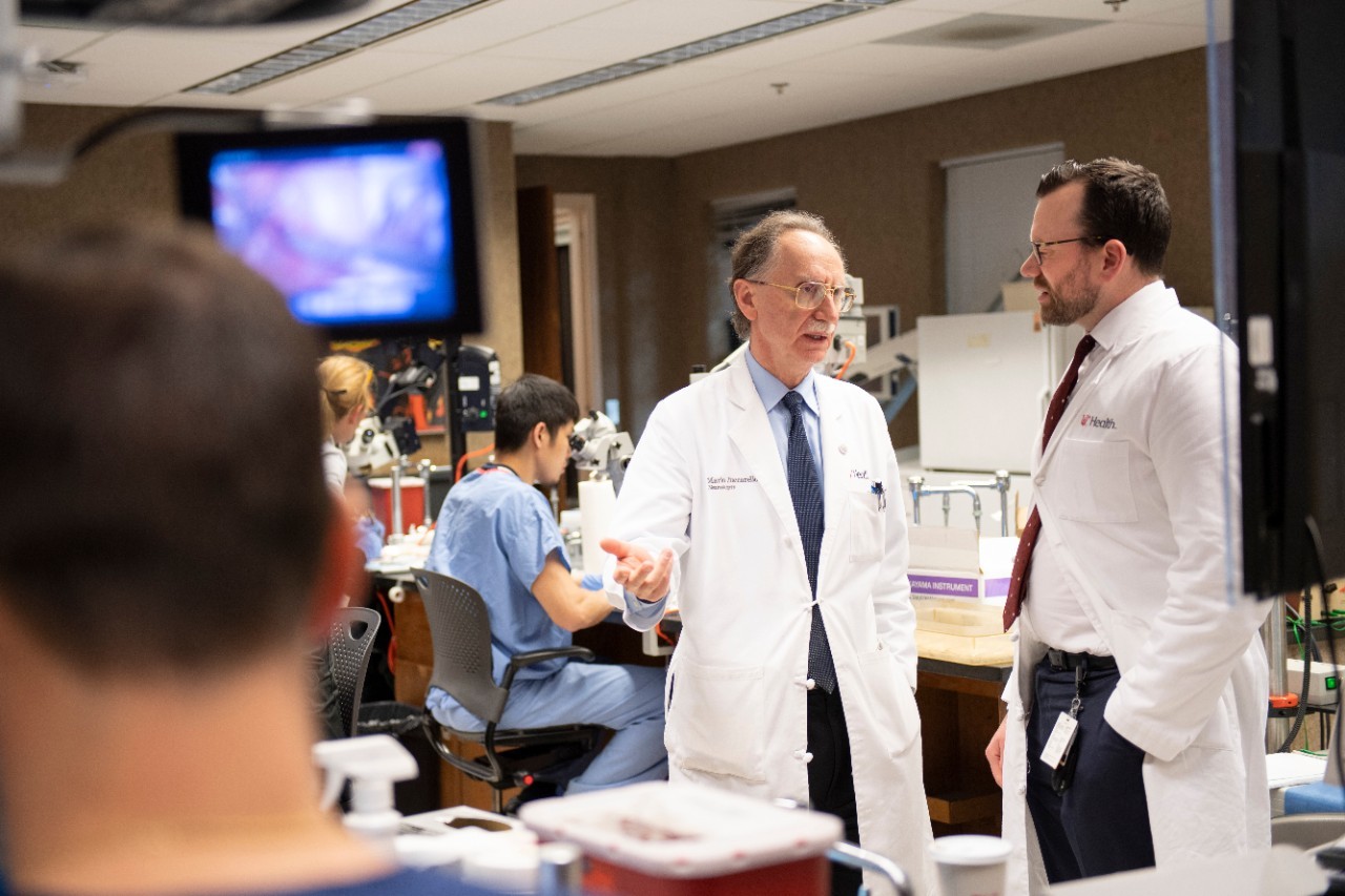 Two men in lab coats talk with each other in a laboratory